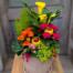 A second view of the Floral Flames arrangement from The Watering Can, showcasing white blooms and lush tropical foliage in an elegant white container.