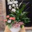 A second view of the Lily Lullaby arrangement from The Watering Can, showing the full profile of its white calla lilies and layered tropical foliage.