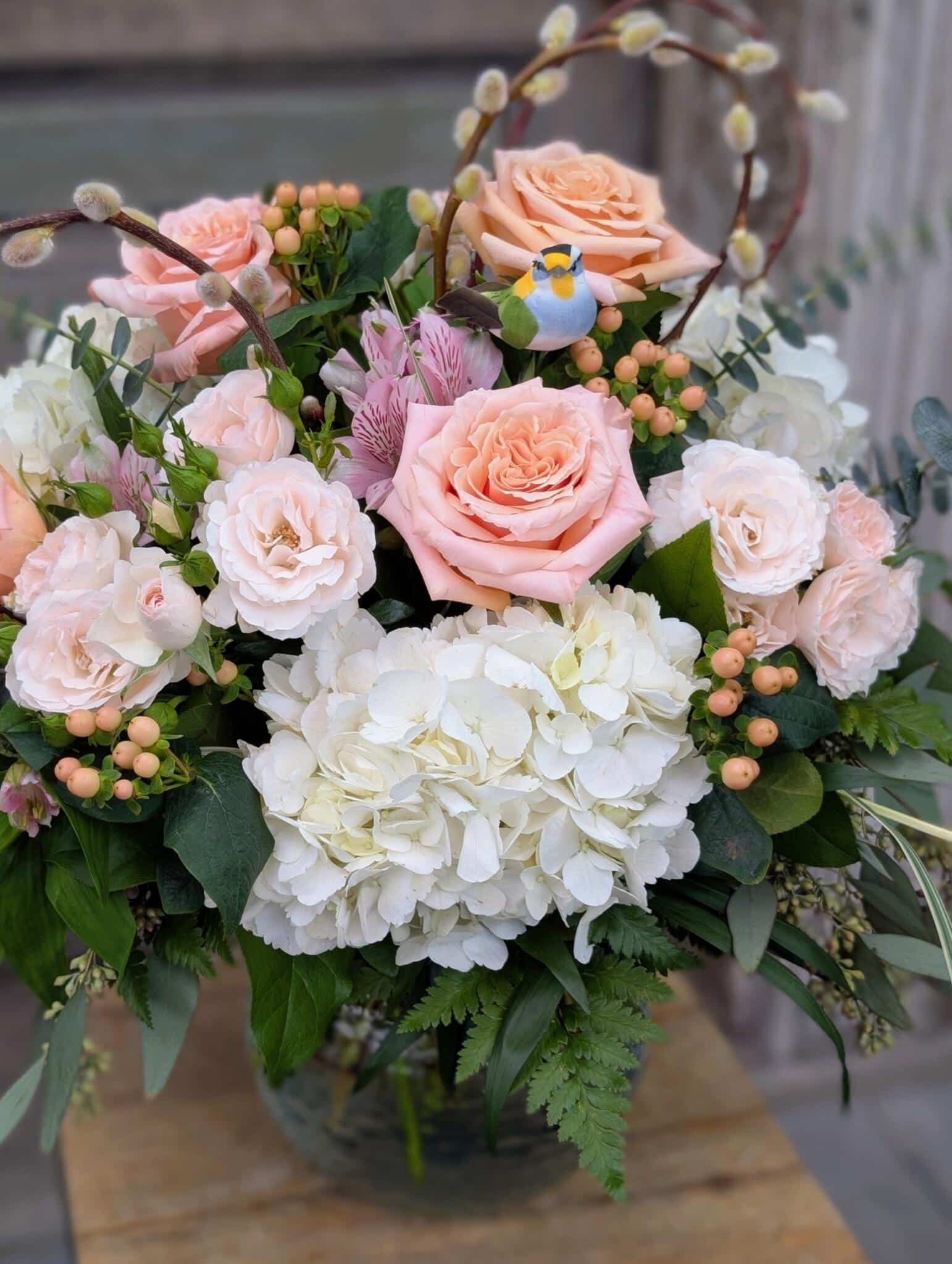 A lush Mother's Nest arrangement featuring soft pink roses and white hydrangea in a round decorative bowl.