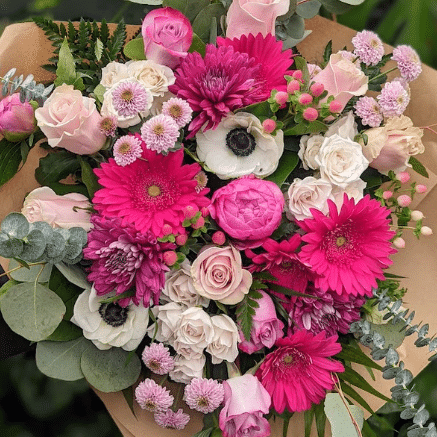 A close-up overhead view of soft pink, white, and blush flowers including ranunculus and anemones in full spring bloom.