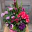 The Pinky Promise arrangement featuring bold hot pink and magenta blooms including carnations in a round ceramic vessel.
